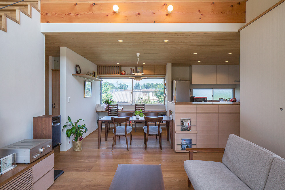 Cette image montre une salle à manger ouverte sur le salon asiatique avec un mur blanc, un sol en bois brun et un sol marron.
