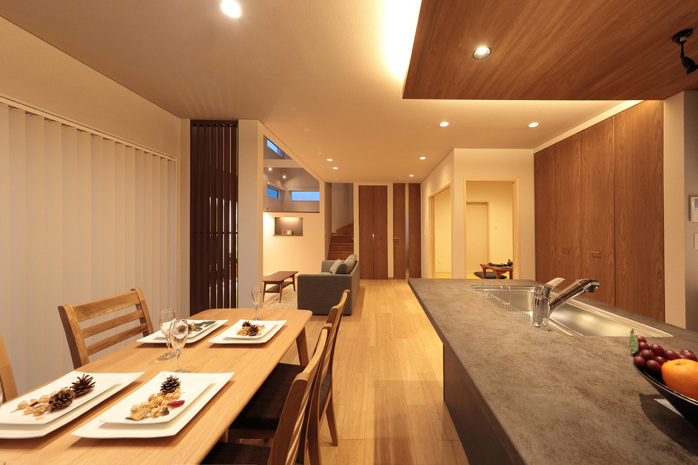 Imagen de comedor minimalista grande abierto con paredes blancas, suelo de madera clara y suelo marrón