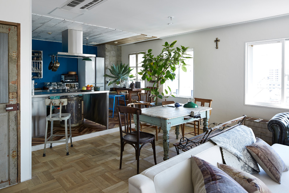 Immagine di una sala da pranzo aperta verso il soggiorno mediterranea con pareti blu, parquet chiaro e pavimento beige