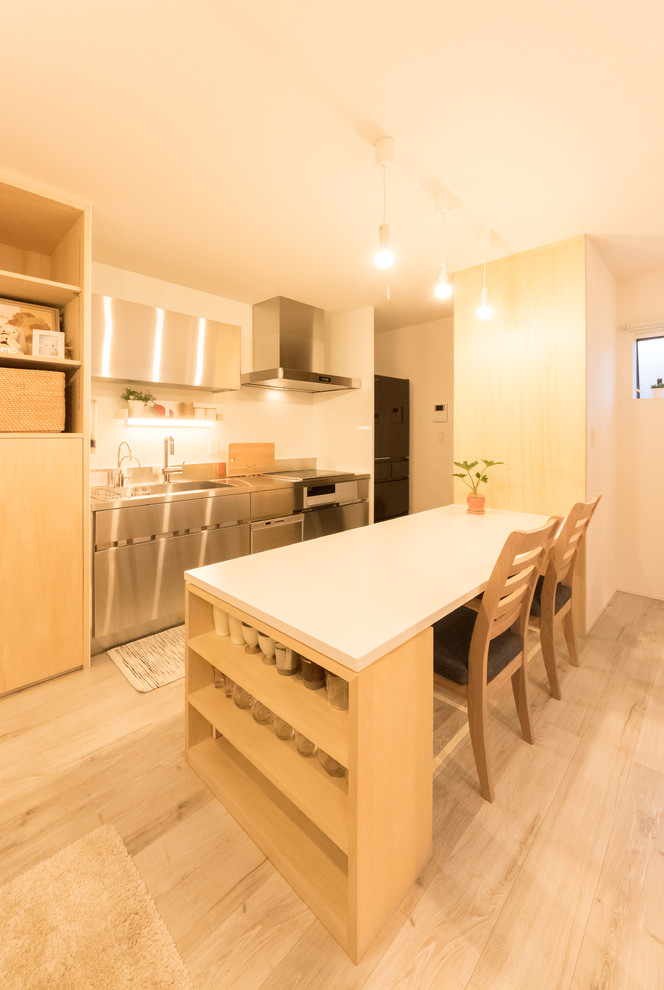 Cette image montre une petite salle à manger nordique avec un mur blanc, parquet clair et un sol marron.