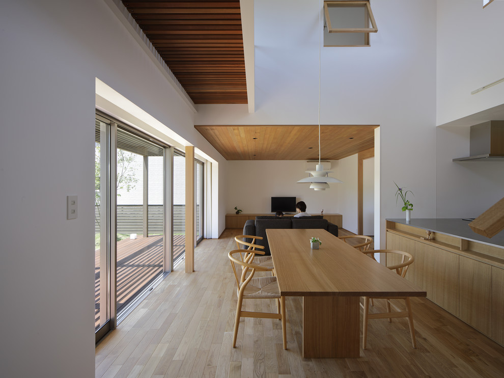 На фото: гостиная-столовая в стиле модернизм с белыми стенами, паркетным полом среднего тона и коричневым полом с