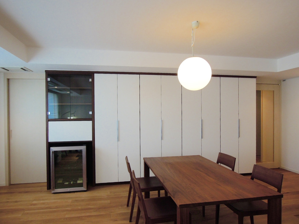 Photo of a modern open plan dining room in Tokyo with white walls, medium hardwood flooring and brown floors.