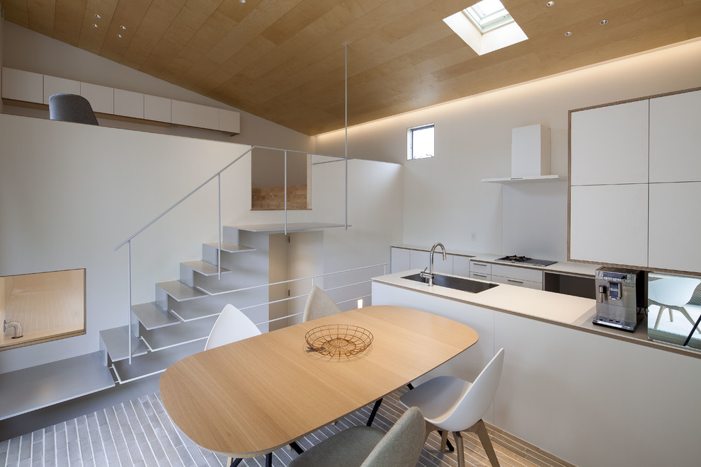 Immagine di una sala da pranzo aperta verso la cucina etnica con pareti bianche e pavimento grigio