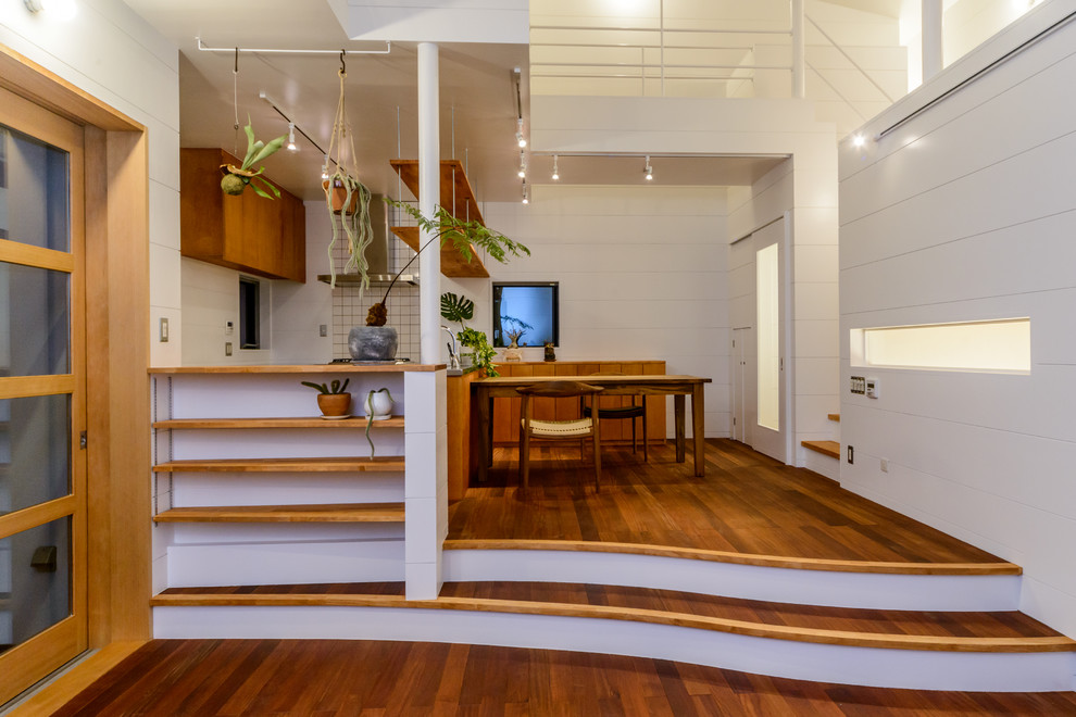 Example of a beach style medium tone wood floor and brown floor great room design in Other with white walls