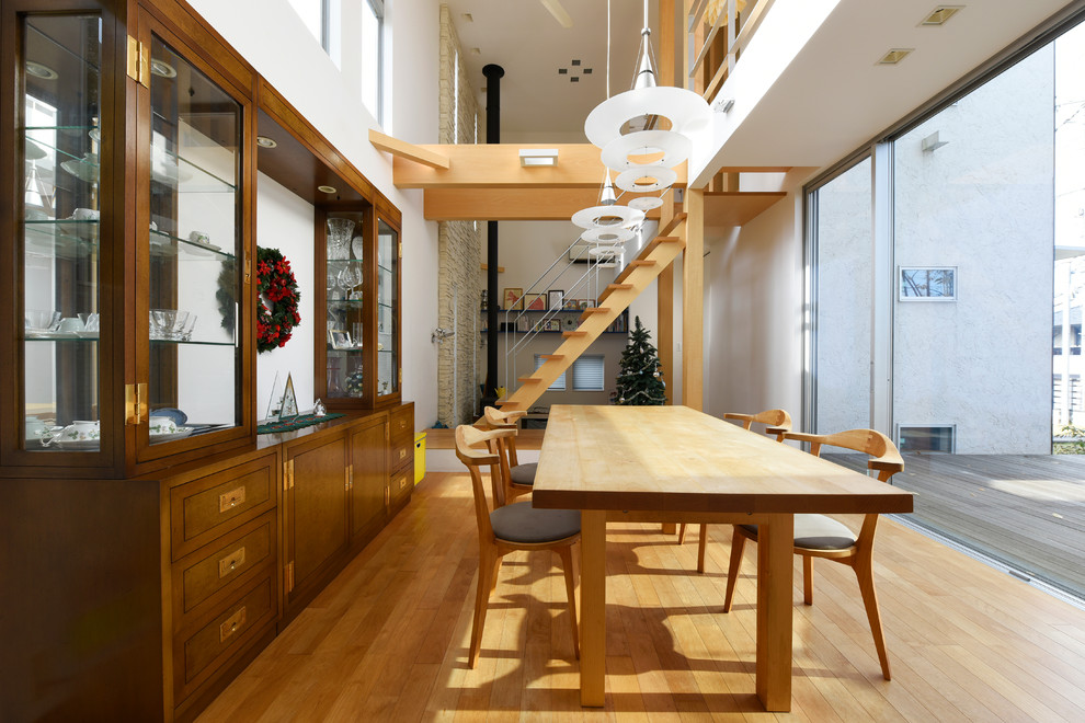 Esempio di una sala da pranzo aperta verso il soggiorno contemporanea con pareti bianche, pavimento in legno massello medio e stufa a legna