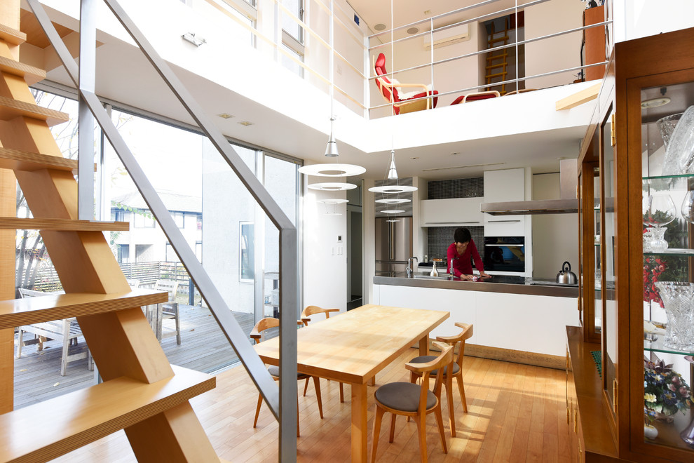 Immagine di una sala da pranzo aperta verso la cucina contemporanea con pareti bianche e pavimento in legno massello medio