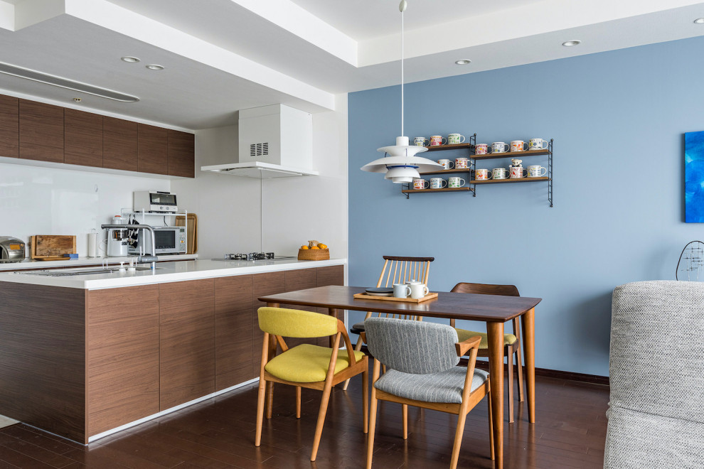 Cette image montre une grande salle à manger ouverte sur le salon nordique avec un mur bleu et parquet foncé.