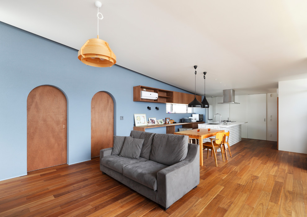 Cette image montre une salle à manger ouverte sur le salon design avec un mur bleu, un sol en bois brun et un sol marron.