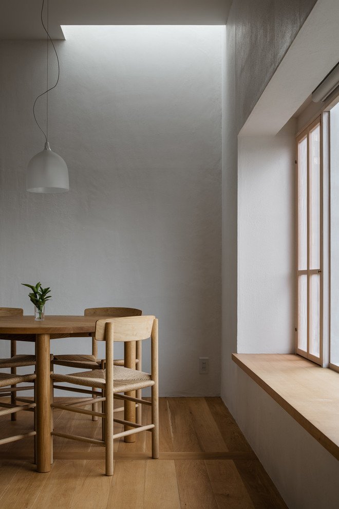 Skandinavisches Esszimmer mit weißer Wandfarbe und braunem Holzboden in Tokio