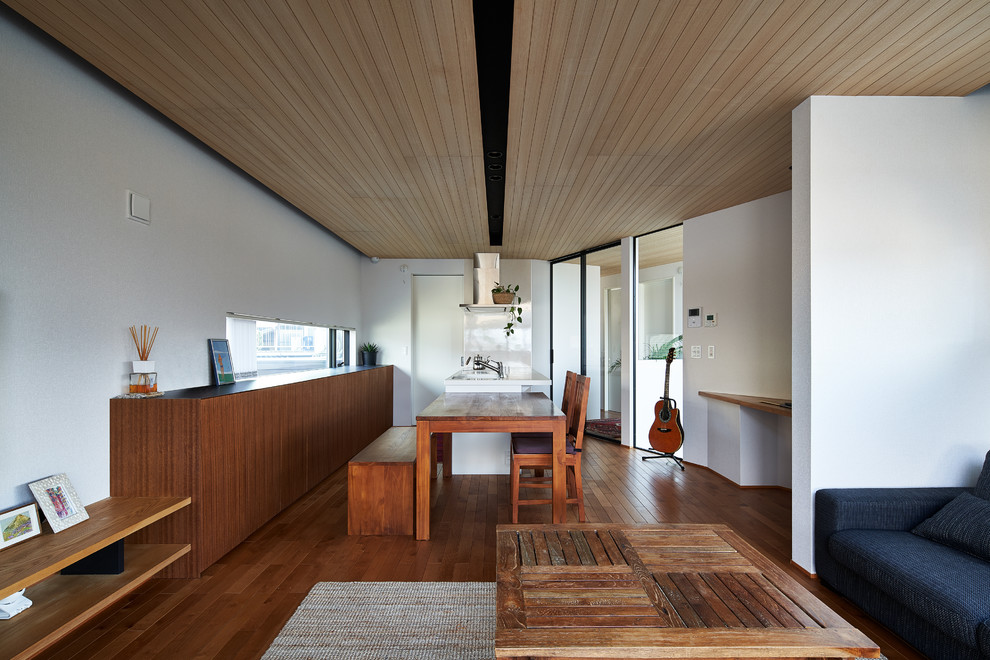 Cette photo montre une salle à manger ouverte sur le salon asiatique avec un mur blanc, un sol en bois brun et un sol marron.
