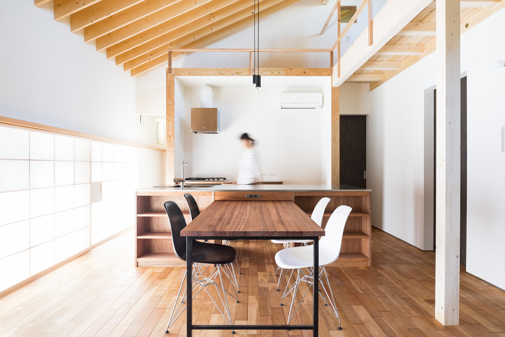 Cette photo montre une salle à manger ouverte sur la cuisine tendance avec un sol en bois brun, mur métallisé et un sol marron.
