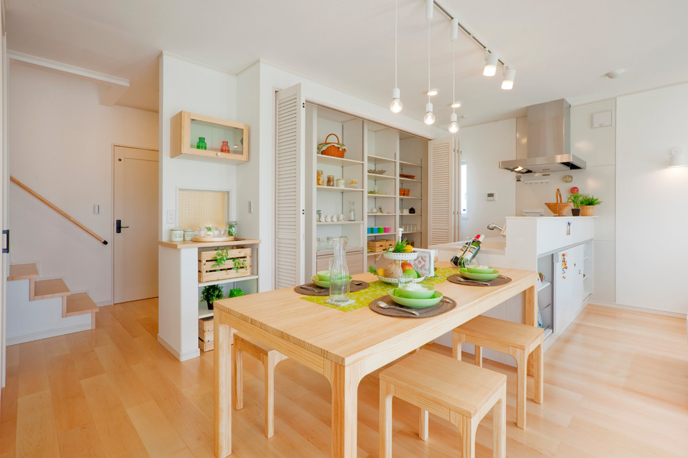 Idée de décoration pour une salle à manger ouverte sur le salon nordique avec un mur blanc, parquet clair et un sol marron.
