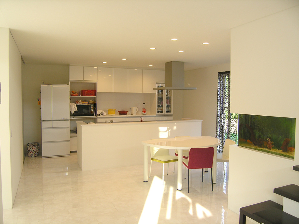 Modern inredning av ett kök med matplats, med vita väggar, linoleumgolv, en öppen vedspis, en spiselkrans i tegelsten och vitt golv