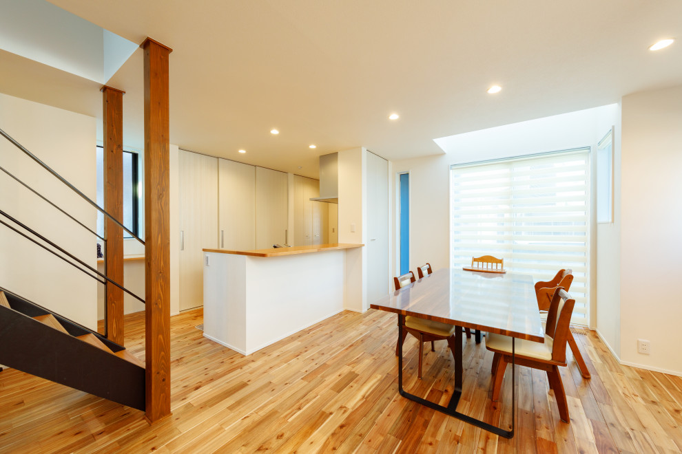 Foto di una sala da pranzo aperta verso il soggiorno minimalista di medie dimensioni con pareti bianche, pavimento in legno massello medio, pavimento marrone, soffitto in carta da parati e carta da parati