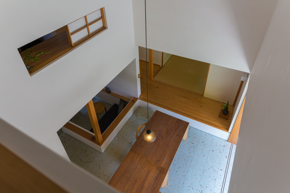 Cette image montre une petite salle à manger ouverte sur le salon minimaliste avec un mur blanc, un poêle à bois, un manteau de cheminée en pierre, un sol blanc et un plafond décaissé.