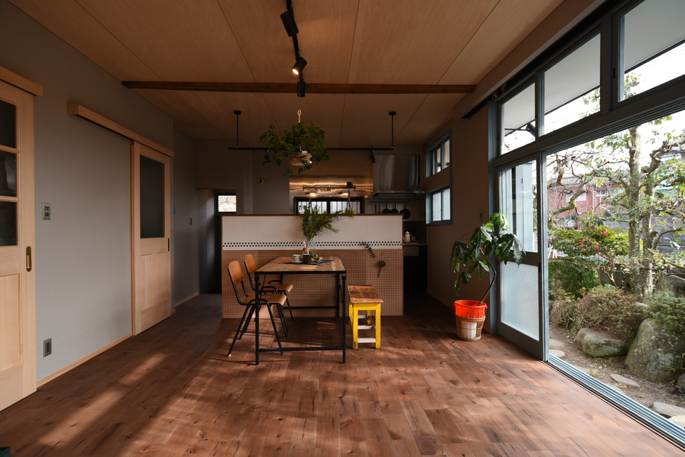 Idée de décoration pour une salle à manger ouverte sur le salon asiatique avec un mur gris, un sol en bois brun et un sol marron.