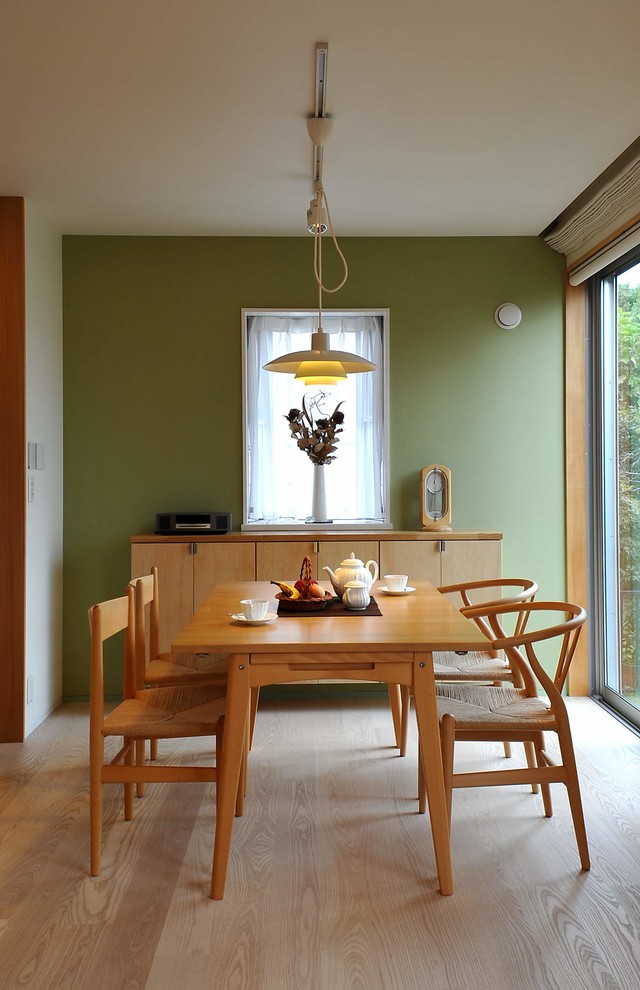 Inredning av en modern mellanstor matplats med öppen planlösning, med gröna väggar, plywoodgolv och beiget golv