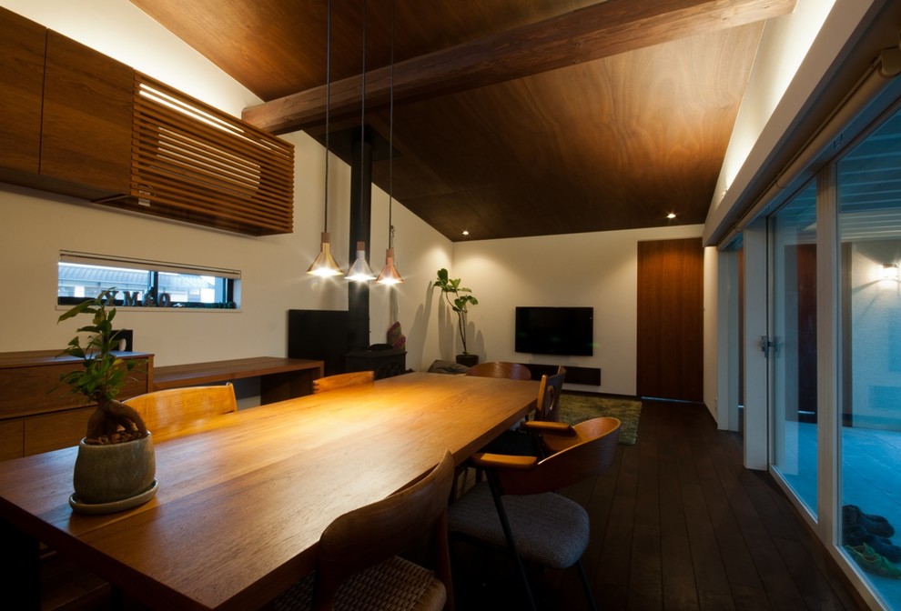 Modernes Esszimmer mit weißer Wandfarbe, dunklem Holzboden und braunem Boden in Sonstige