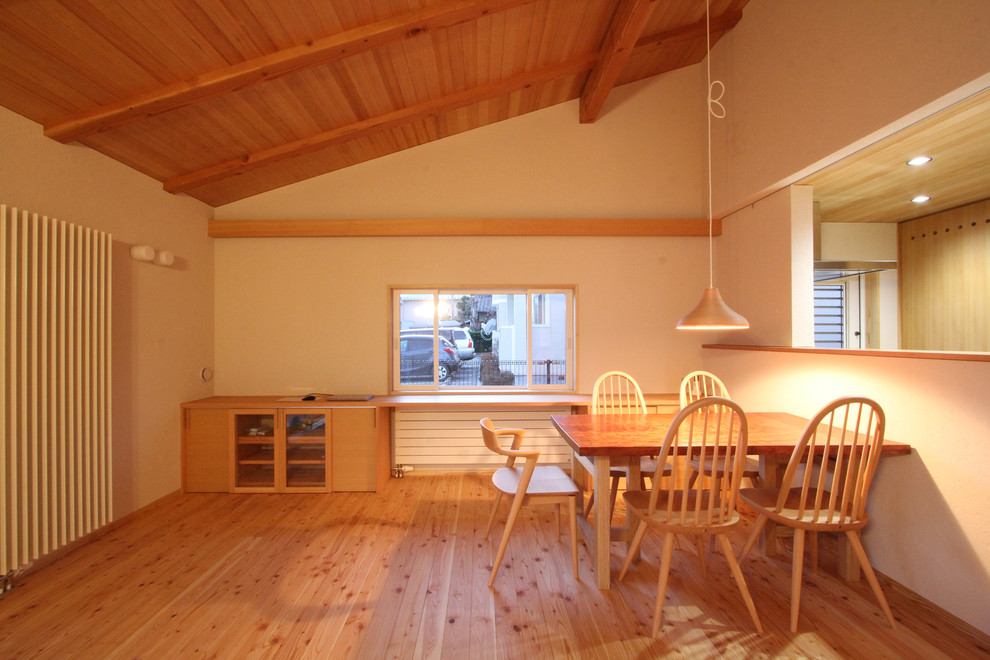 Réalisation d'une salle à manger nordique avec un mur blanc, un sol en bois brun et un sol marron.