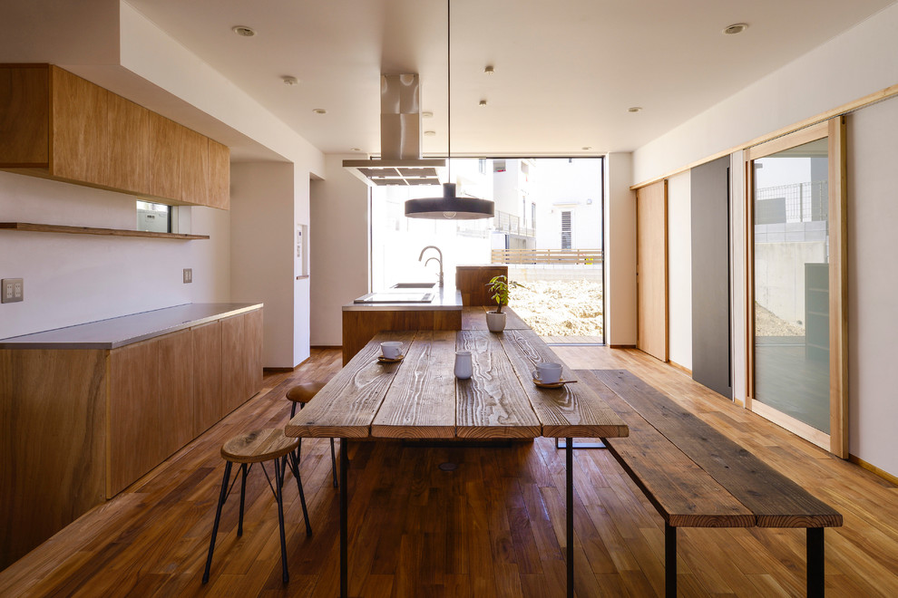 Esempio di una sala da pranzo aperta verso la cucina industriale con pareti bianche, nessun camino e pavimento in legno massello medio