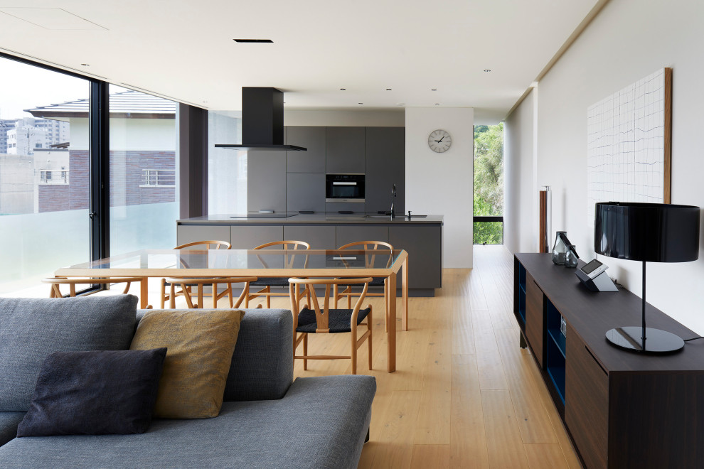 Idée de décoration pour une salle à manger ouverte sur le salon design de taille moyenne avec un mur gris, un sol en bois brun et un sol marron.