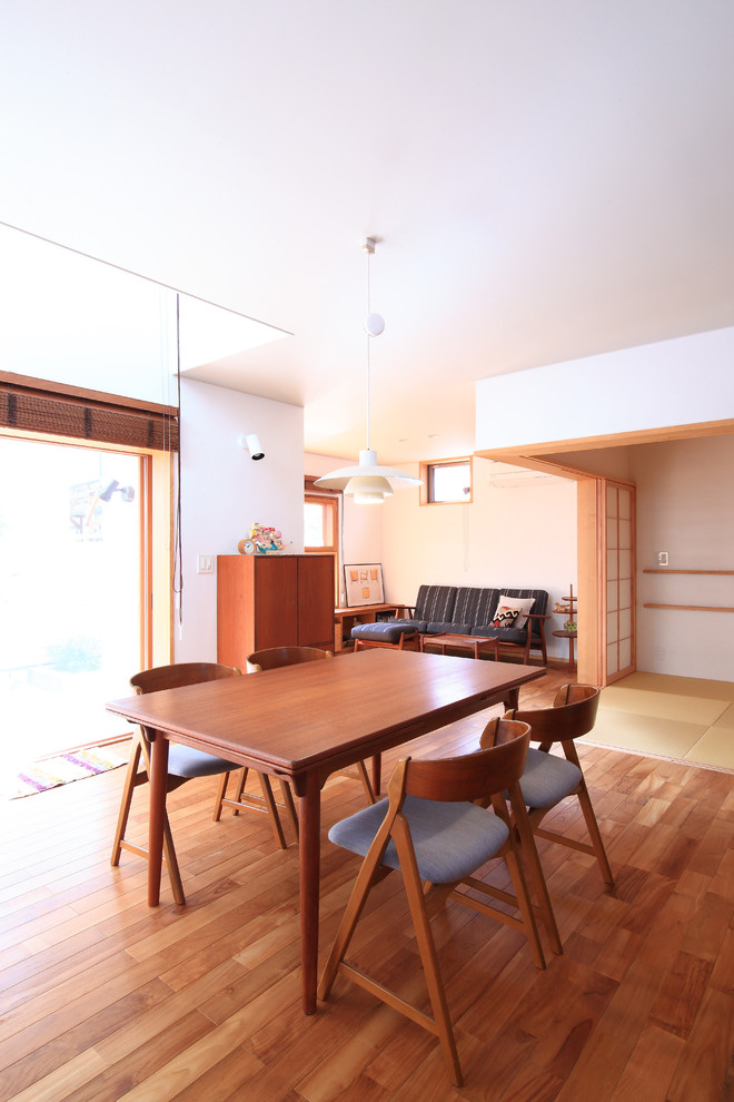 Immagine di una sala da pranzo aperta verso il soggiorno nordica con pareti bianche, parquet scuro e pavimento marrone