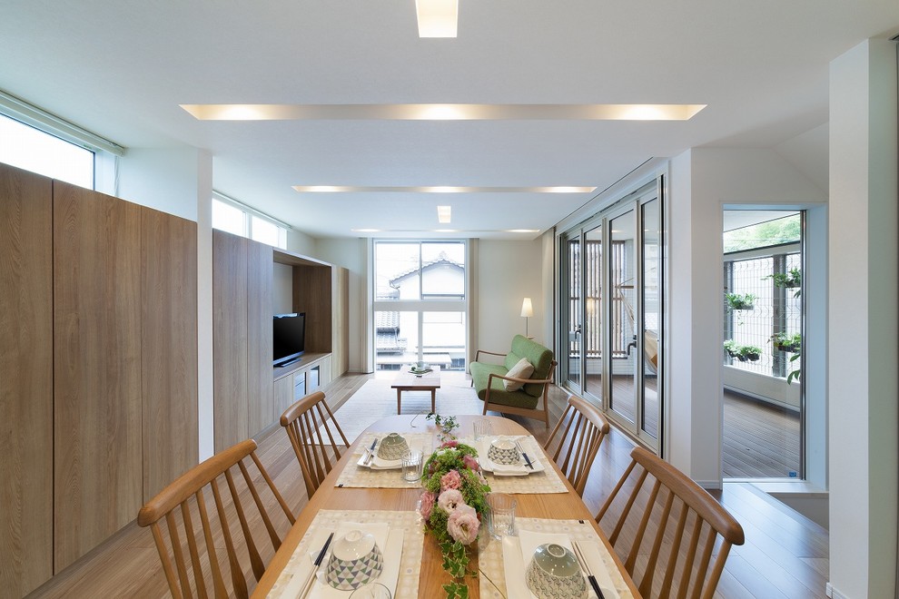 Exemple d'une salle à manger ouverte sur le salon tendance avec un mur blanc, un sol en bois brun et un sol marron.