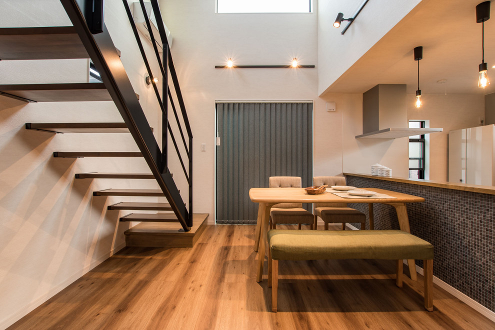 Cette image montre une petite salle à manger ouverte sur la cuisine minimaliste avec du papier peint, un mur blanc, un sol en bois brun, aucune cheminée, un sol marron et un plafond en papier peint.