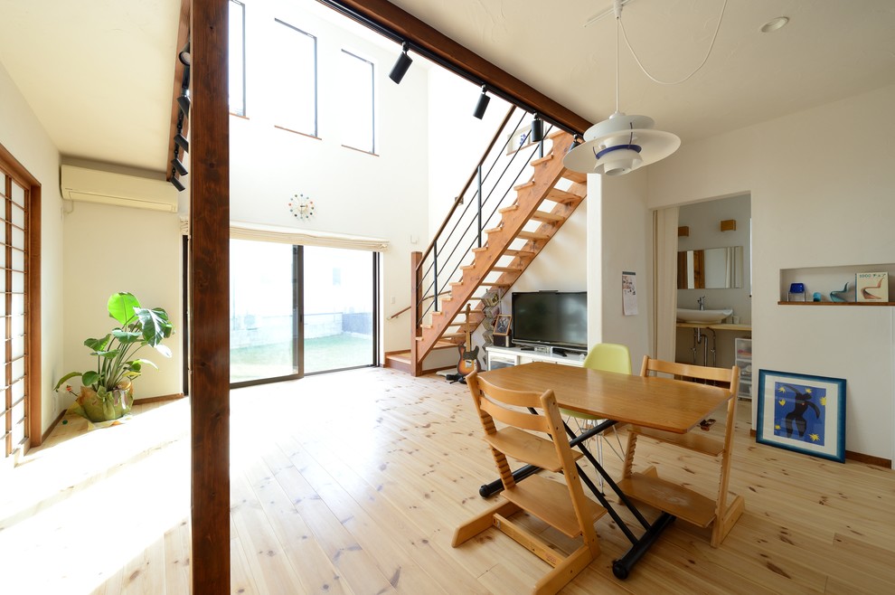 World-inspired open plan dining room in Nagoya with white walls, no fireplace, light hardwood flooring and brown floors.