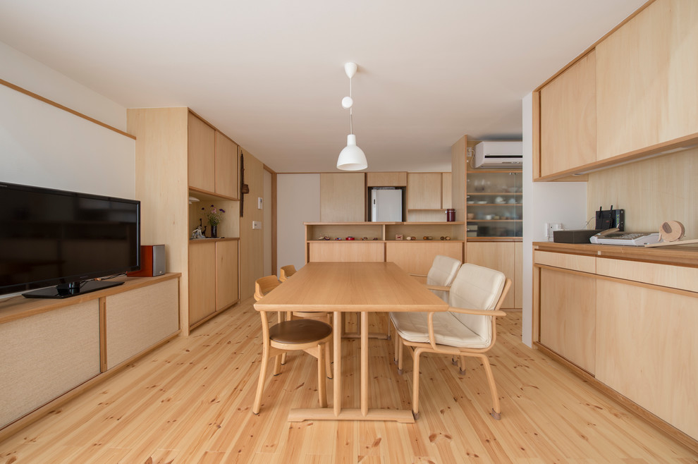 Esempio di una sala da pranzo aperta verso il soggiorno etnica con pareti bianche, parquet chiaro e pavimento marrone