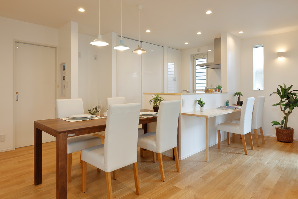 Idées déco pour une salle à manger ouverte sur le salon moderne avec un mur blanc, parquet clair et un sol marron.