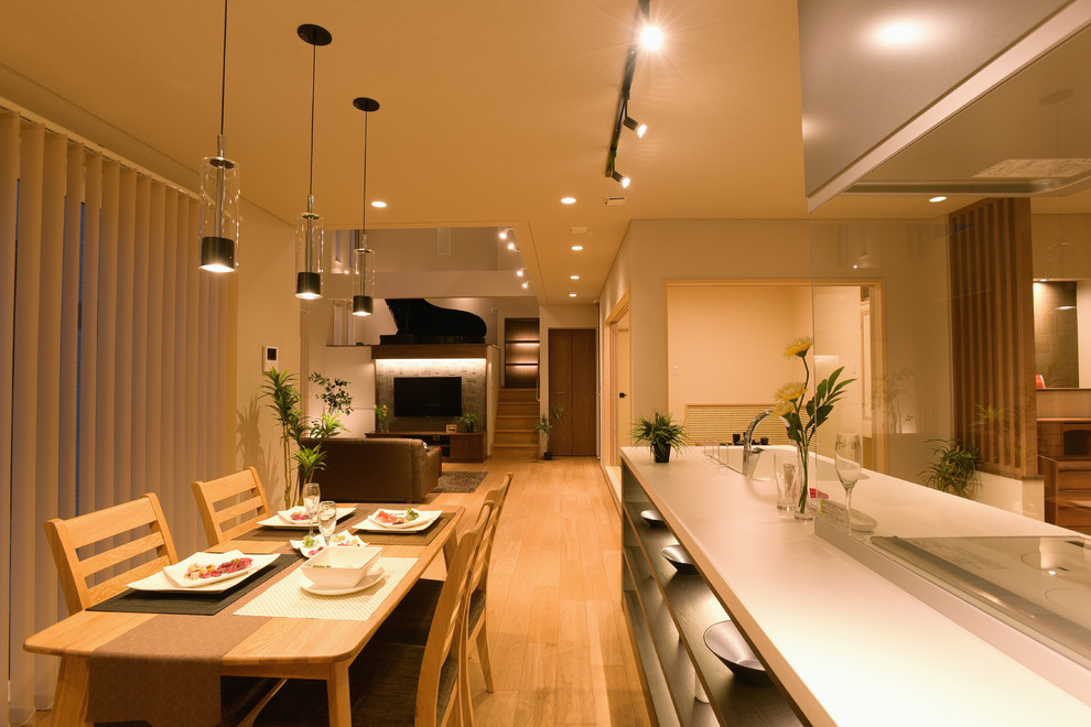 Cette image montre une salle à manger ouverte sur le salon asiatique avec un mur blanc, parquet clair et un sol marron.