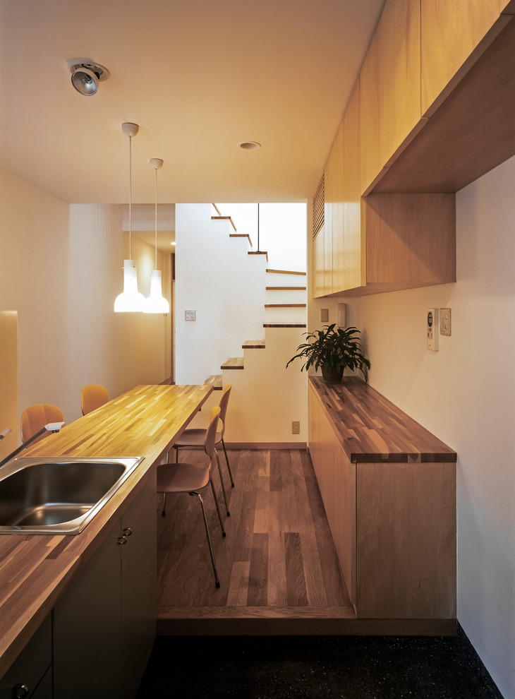 Moderne Wohnküche mit weißer Wandfarbe und braunem Holzboden in Sonstige
