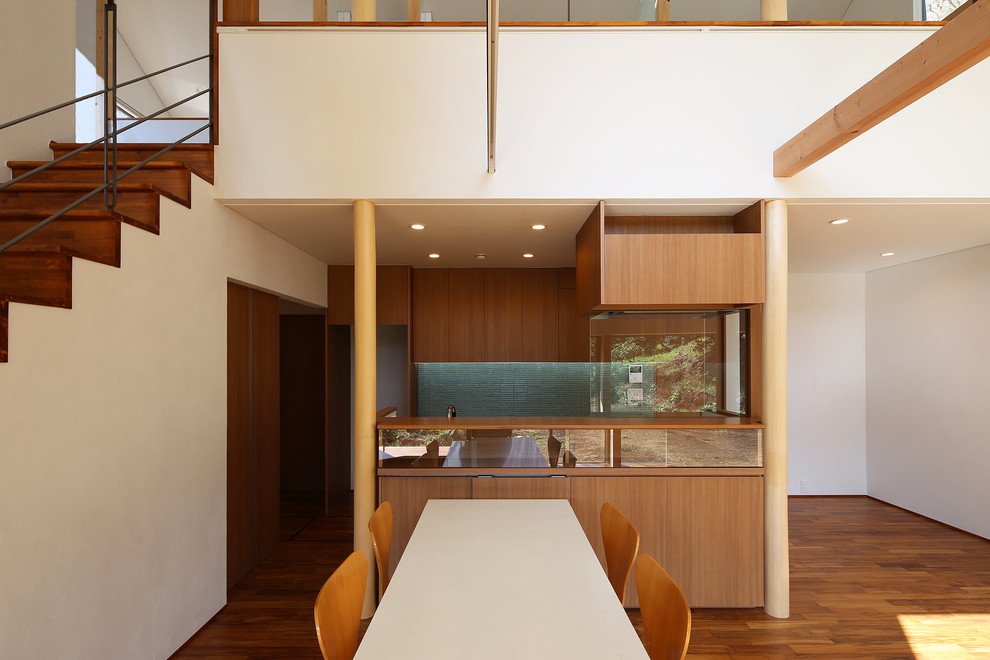 Inspiration pour une salle à manger ouverte sur le salon minimaliste de taille moyenne avec un mur blanc, un sol en bois brun et un sol marron.