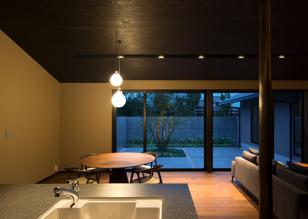 Идея дизайна: маленькая гостиная-столовая в восточном стиле с коричневыми стенами, полом из фанеры и коричневым полом без камина для на участке и в саду