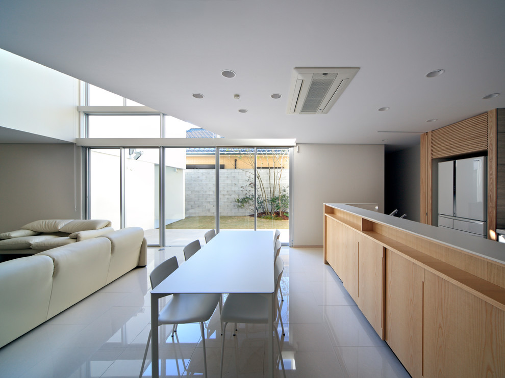 Aménagement d'une salle à manger ouverte sur le salon moderne avec un mur blanc, un sol en carrelage de céramique et un sol blanc.