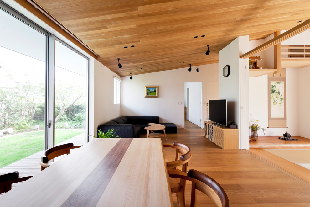 Aménagement d'une salle à manger ouverte sur le salon asiatique de taille moyenne avec un mur blanc, un sol en bois brun, un sol marron et aucune cheminée.