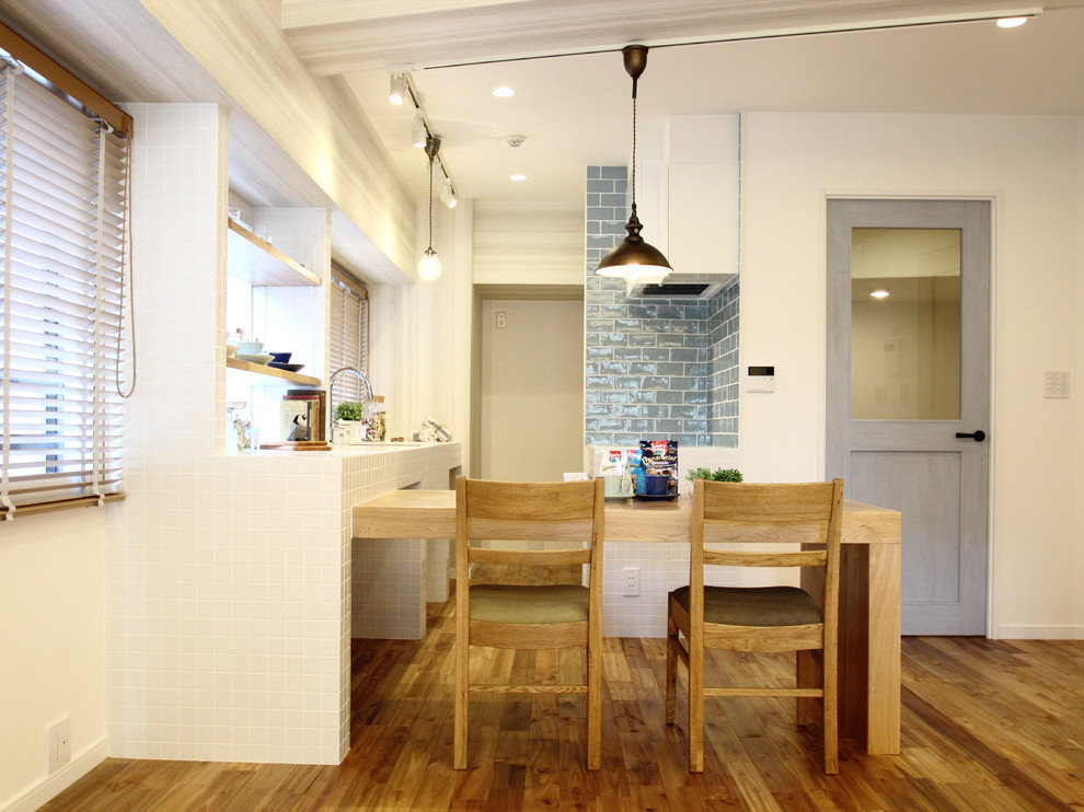 Imagen de comedor nórdico abierto con paredes blancas, suelo de madera en tonos medios y suelo marrón