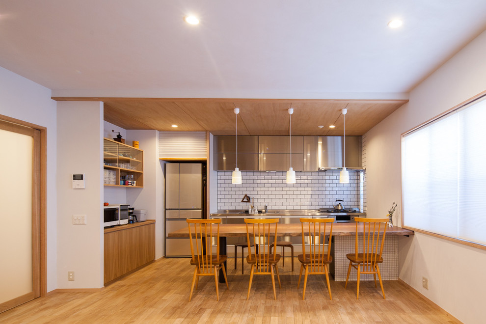 Exemple d'une salle à manger ouverte sur le salon moderne avec un mur blanc, un sol en bois brun et un sol marron.