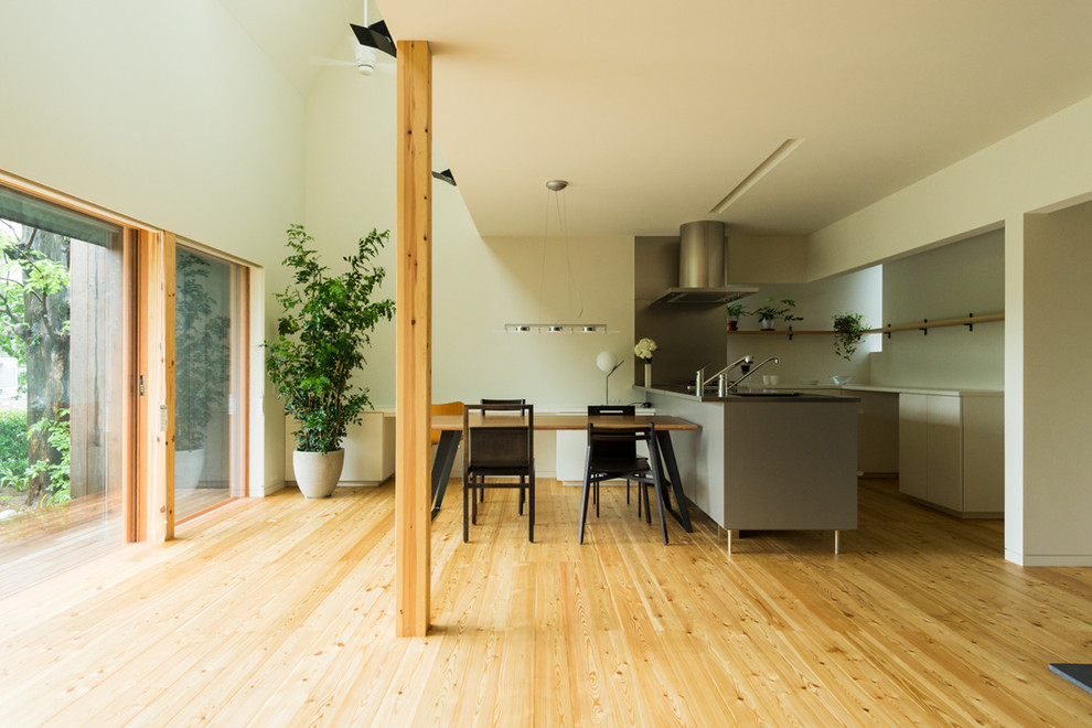 Esempio di una sala da pranzo aperta verso il soggiorno contemporanea con pareti bianche, pavimento in legno massello medio e pavimento marrone