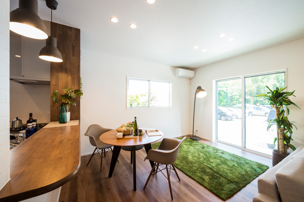Esempio di una piccola sala da pranzo aperta verso il soggiorno moderna con pareti bianche, pavimento in legno verniciato e pavimento marrone