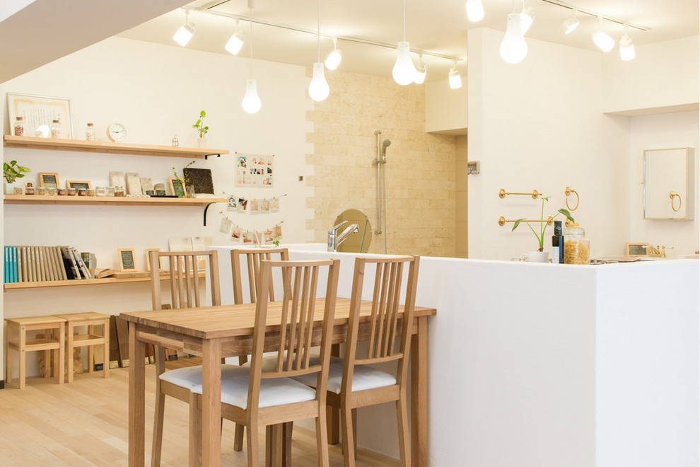 Foto di una sala da pranzo aperta verso la cucina minimal con pareti bianche e parquet chiaro