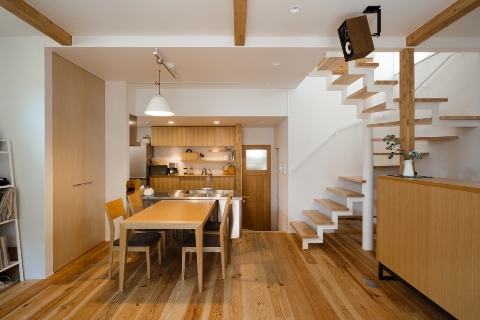Aménagement d'une salle à manger ouverte sur le salon contemporaine avec un mur blanc, un sol en bois brun et un sol marron.