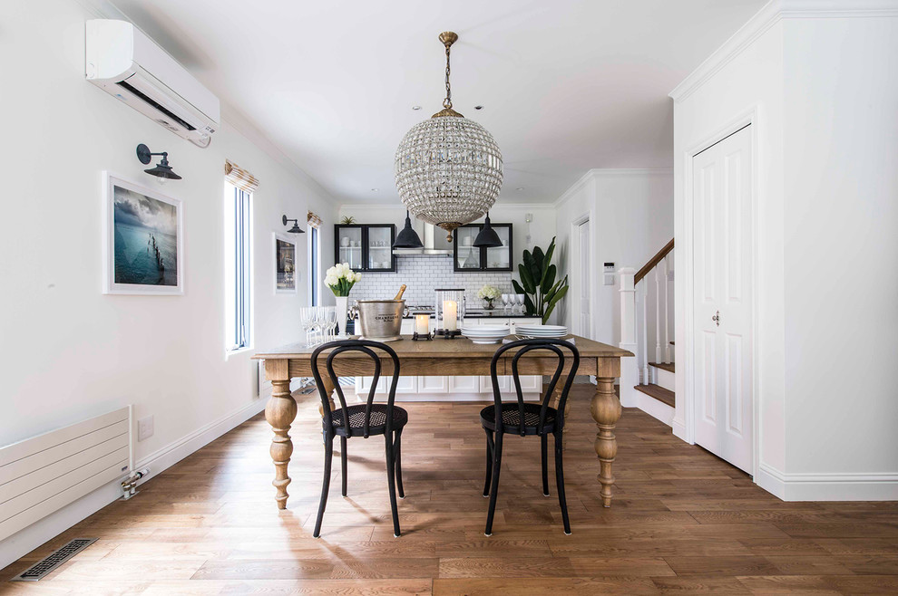 Foto di una sala da pranzo aperta verso il soggiorno tradizionale con pareti bianche, pavimento in legno massello medio e pavimento marrone