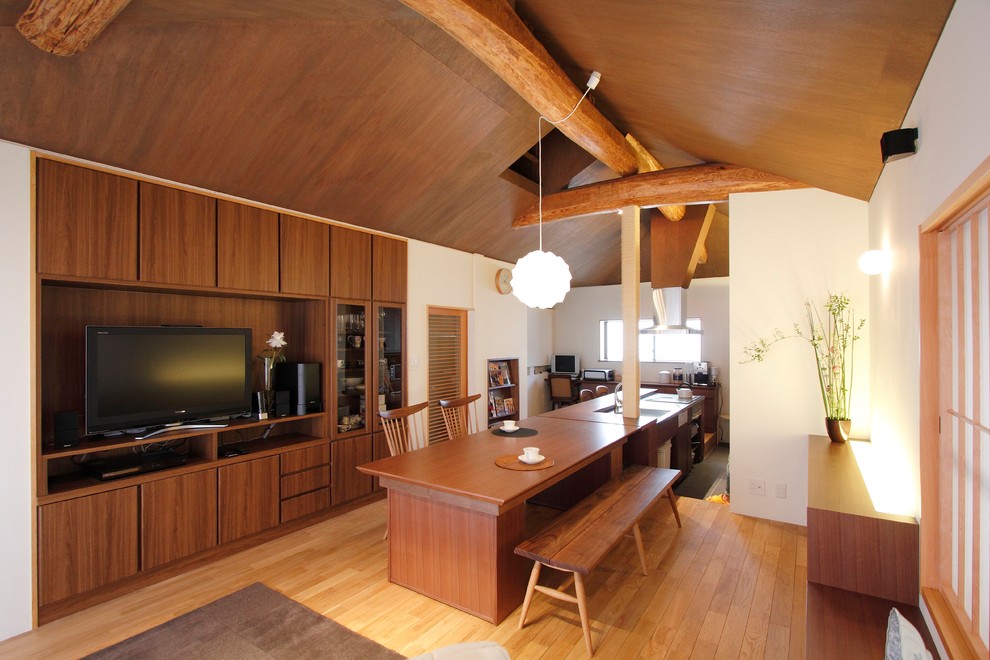 Esempio di una sala da pranzo aperta verso il soggiorno etnica con pareti bianche, pavimento in legno massello medio e pavimento marrone