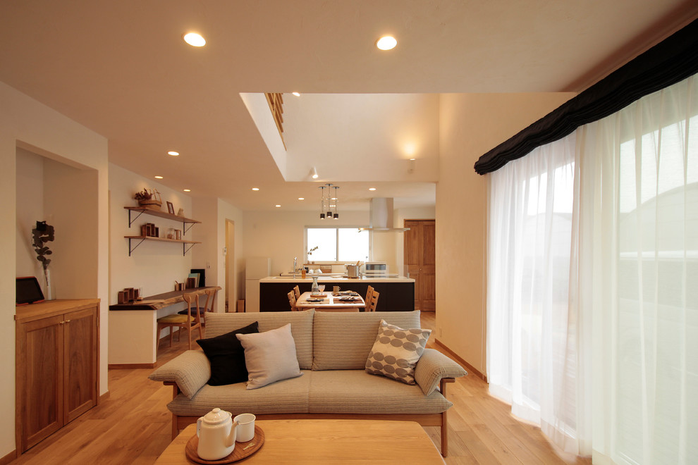 Foto di una sala da pranzo aperta verso il soggiorno moderna con pareti bianche, parquet chiaro e nessun camino