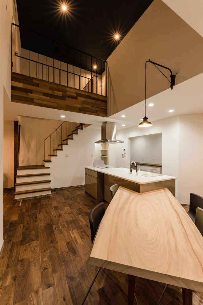Cette image montre une salle à manger ouverte sur le salon minimaliste avec un mur blanc, parquet foncé et un sol marron.