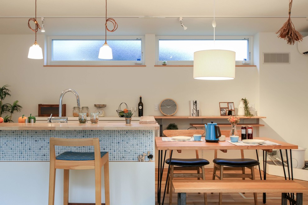 Cette photo montre une salle à manger scandinave avec un mur blanc, un sol en bois brun et un sol marron.