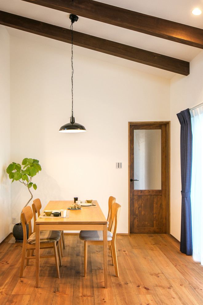 Réalisation d'une salle à manger ouverte sur le salon asiatique avec un mur blanc, un sol en bois brun et un sol marron.