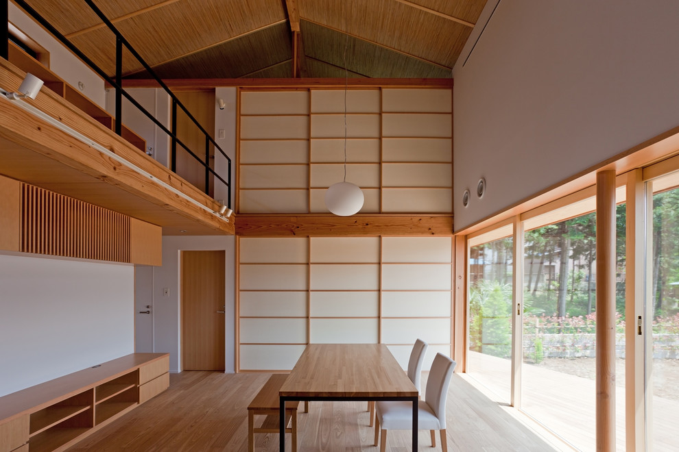 Cette image montre une salle à manger asiatique avec un mur blanc, un sol en bois brun et un sol marron.